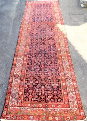 A Persian red ground runner, the central field decorated with small medallions and floral motifs, within repeating floral and geometric borders, 500cm x 157cm.