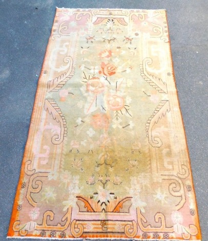 An Peking pale green ground rug, decorated centrally with bold flowers and leaves, within floral and foliate borders, 328cm x 135cm.