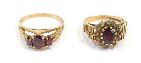 Two 9ct gold garnet dress rings, comprising a three stone ring, size T½, and a cluster set with CZ stones, size O½, 7.7g all in. (2)