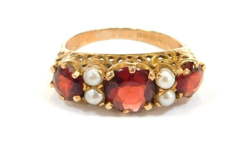 A 9ct gold dress ring, set with three round brilliant cut garnets and four cultured pearls, in a raised shank with a claw setting, size O½, 3.1g all in.