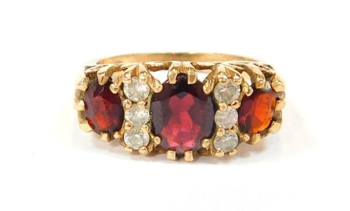 A 9ct gold dress ring, set with three oval garnets, and six imitation diamonds, in a raised claw setting, size O½, 5g all in.