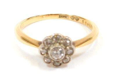 An 18ct gold diamond dress ring, the central floral cluster set with tiny diamonds, in rub over platinum setting, on a yellow metal band stamped 18, size N, 2.7g all in.