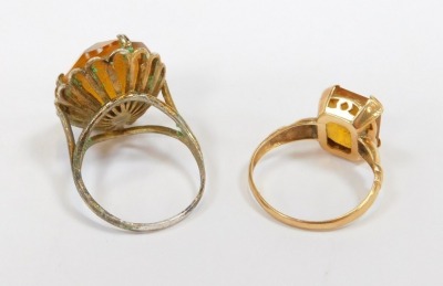 Two dress rings, comprising a rectangular cut citrine, in a raised basket, on yellow metal band stamped 14K, size O, 6g all in, and a silver and imitation citrine dress ring. (2) - 2