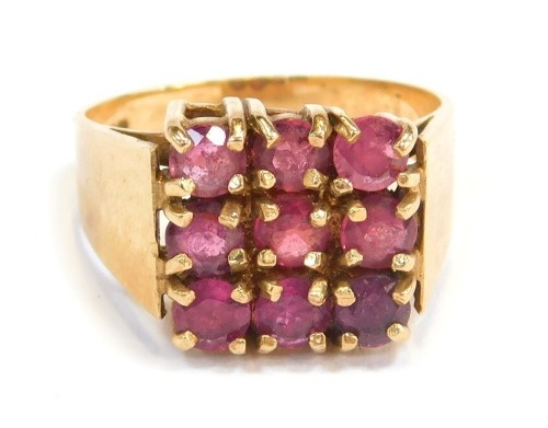 A 9ct gold dress ring, the square set panel with nine garnets, each in claw setting, on a plain yellow metal band, R, 5.7g all in.