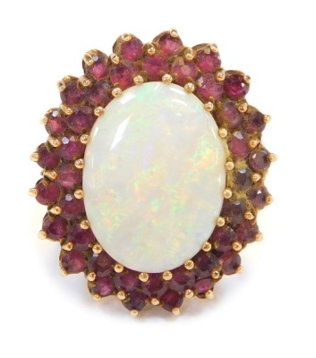 A cluster ring, with oval cut imitation opal surrounded by garnets, in a yellow metal setting, unmarked, believed to be 9ct gold, ring size Q, 11.9g all in.