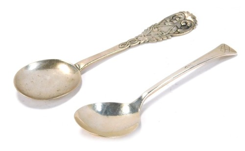 A Georgian silver spoon, with a round flattened bowl, the handle cast with scroll and leaf motifs, hall marks rubbed, 1.34oz, together with a plated spoon, with a reverse hammered bowl, the handle with diamond shaped engraving.