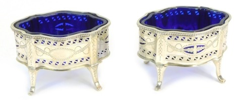 A pair of George V silver salts, of serpentine form, with pierced and engraved decoration, with blue glass liners, Goldsmiths and Silversmiths Company Limited, Sheffield 1925, 4.54oz.