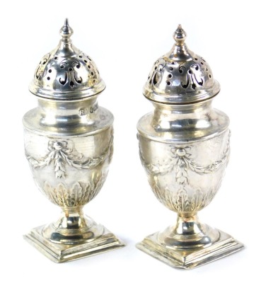 A pair of Victorian silver salt and pepper pots, each with a pierced and fluted top, on Neoclassical swag design body, on a square foot, maker HA, Sheffield 1896, 4.80oz.