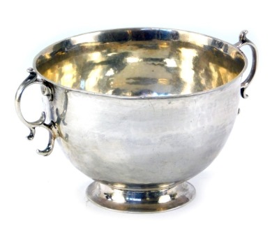 A Britannia silver twin handled sugar bowl or porringer, the handles of double scroll form, with a plain body, maker's mark and year letter worn and indecipherable, 4.86oz.