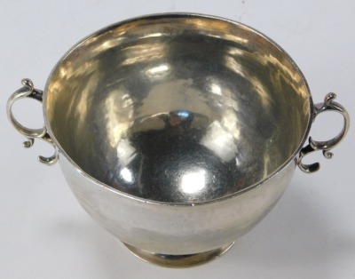 A Britannia silver twin handled sugar bowl or porringer, the handles of double scroll form, with a plain body, maker's mark and year letter worn and indecipherable, 4.86oz. - 2