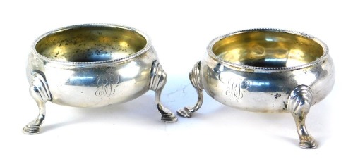 A pair of Victorian circular silver salts, each with a reeded border, on tripod shell capped legs, bearing the initials RV, London 1850, 3.53oz.