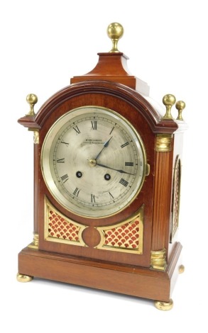 An Edwardian mahogany cased mantel clock, the silvered Roman numeric dial bearing name W. Greenwood Leeds & Huddersfield, eight day, movement no 208442, the case of architectural form, with brass orb finial, brass capped pilasters, on a rectangular steppe