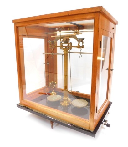 A set of brass laboratory scales, contained in an oak and perspex case, 53cm high.