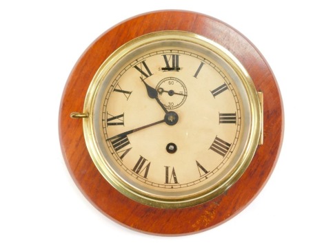 A brass cased ship's clock, the enamel circular dial bearing Roman numerals, subsidiary seconds dial, thirty hour movement, on an oak mount, 27cm diameter.