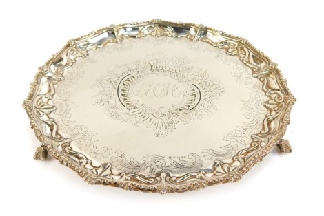 A Victorian silver plated piecrust salver, initialled centrally, amongst engraved flowers, scrolls, etc, raised on three ball and claw feet, 31cm diameter.