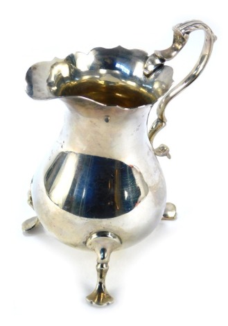 A George V silver cream jug, with a fluted and moulded border, with acanthus leaf shaped handle, on tripod feet, Chester hallmarks rubbed, 8cm high, 3.25oz.