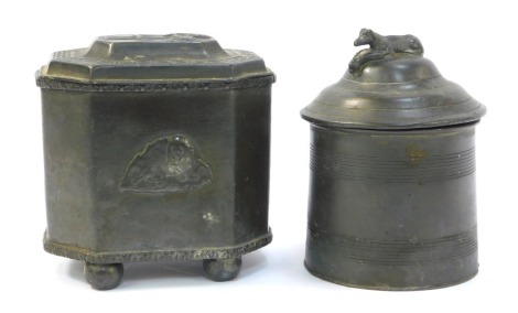 Two 19thC pewter tobacco jars, one of cylindrical form, banded decoration, the lid cast with model of a recumbent greyhound, 13cm high, the other of cylindrical form, decorated with Greek key decoration, the lid cast with a figure, etc, 11cm high. (2)