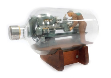 A Precision Models (Luton) model lathe in a bottle, on stand, 30cm high, 42cm wide.