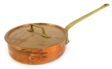 A shallow copper saucepan and lid, with brass handle, 26cm diameter.