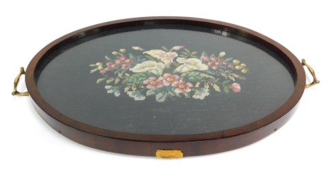 A late 19th/early 20thC mahogany tray, inset centrally with a floral embroidered panel, two brass handles, 57cm wide.