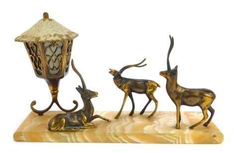 A mid 20thC cast brass and onyx desk stand, modelled as three stylised deer beside lantern, on rectangular marble base, 41cm wide.