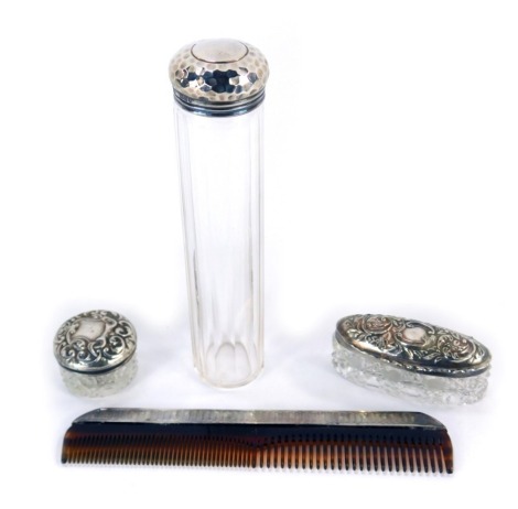 An Edward VII cut glass cylindrical jar with a silver screw lid, London 1906, two further cut glass toilet jars with silver lids, embossed with rococo scrolls, Birmingham 1902 and 1903, and a silver back comb with engine turned decoration, London 1956. (4