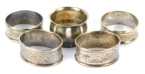 A pair of Elizabeth II napkin rings, with foliate scroll decoration, rectangular vacant reserve, Birmingham 1951, and a further pair of George V napkin rings, Birmingham 1927, 2.24oz, a plated napkin ring. (5)