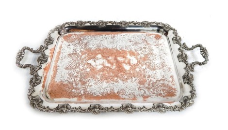 A silver plated tray, the border decorated in relief with grapes and vines, decorated centrally with etched scrolled flowers, etc, 68cm wide.