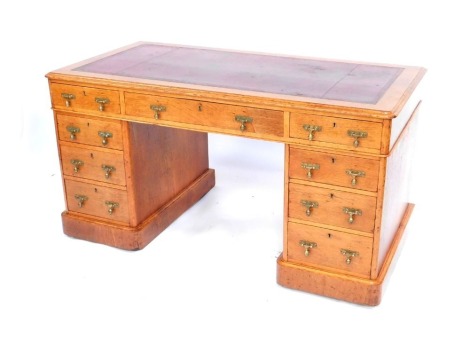 A 19thC oak pedestal desk, the top inset with a tooled red leather panel, with one short and two long drawers, two side pedestals with three drawers, with brass drop handles, on stepped plinth base, on castors, 73cm high, the top 136cm  x 71cm. 