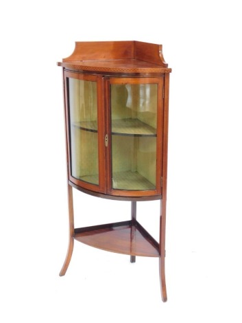 A late 19th/early 20thC mahogany and boxwood and ebony inlaid corner display cabinet, the top with a raised back above two glazed doors enclosing two shelves, with under tier, raised on splayed legs, with key, 136cm high, 59cm wide, 47cm deep.