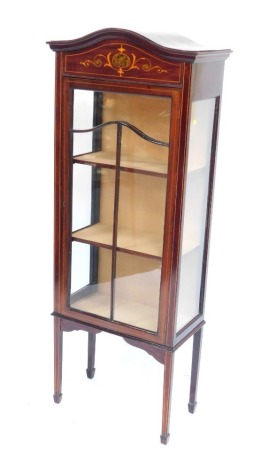 An Edwardian mahogany and inlaid display cabinet, the curved moulded top above an inlaid panel, with panelled glazed door and two glass side panels, enclosing three shelves, raised on splayed legs, 162cm high, 64cm wide, 32cm deep.