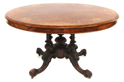 A 19thC walnut burr walnut and inlaid breakfast table, the oval top inlaid with boxwood foliate motifs, above a central turned carved column supported by four turned pilasters raised on four scroll carved legs, on castors, 70cm high, the top 120cm x 94cm.