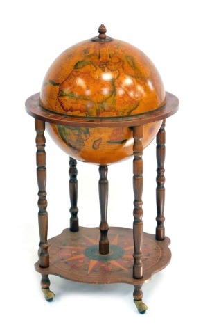 A late 20thC novelty globe drinks trolley, the hinged globe lid opening to reveal a fitted interior, above rim decorated with astrological symbols, raised on turned oak columns, above a sunburst decorated base, on castors, 90cm high.