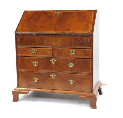 A George III oak bureau, the fall opening to reveal a central semi-secret drawer and two sliding column compartments, flanked by four recesses and eight drawers, above two short above three long drawers, raised on bracket feet, 116cm high, 103cm wide, 55c