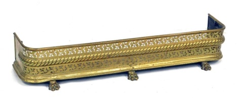 A Victorian brass fender, with a pierced gallery, raised on three lion's paw feet, 118cm wide.