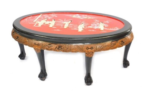 A late 20thC Hong Kong ebonised and carved hardwood oval occasional table, the oval top overlaid with mother of pearl figures in a garden, above a carved frieze and six straight legs on lion's paw feet, 53cm high, 124cm wide, 80cm deep.