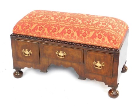 A walnut Ottoman, with a floral and foliate red and gold upholstered drop-in seat, above a chest on chest base, with one long and two deep drawers, raised on bun feet, 62cm high, 101cm wide, 51.5cm deep. 