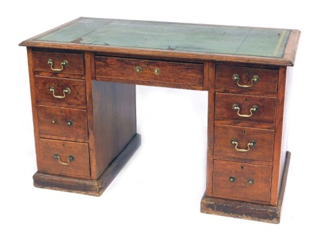 An early 20thC oak twin pedestal desk, with a gilt tooled green leather skiver, above one long and eight short graduated drawers, raised on plinth bases, 74cm high, 122cm wide, 64cm deep.