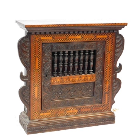 A Jacobean style oak and marquetry inlaid livery cupboard, the out swept pediment over a carved central door, with openwork spindle centrally, within a marquetry frame, and carved foliate scroll sides, raised on a plinth base, 91.5cm high, 95cm wide, 29cm