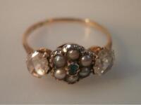 A yellow metal ring set with a seed pearl and green stone cluster