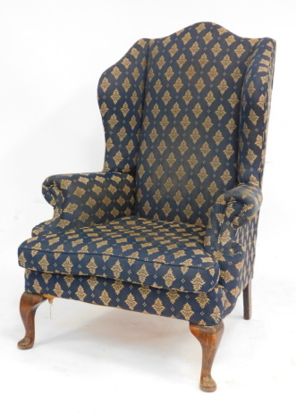 A 20thC wingback armchair, upholstered in blue fabric, on mahogany pad feet.