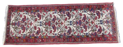 A Turkish cream ground runner, the central field decorated with three vases of flowers, within repeating geometric borders, 194cm x 72cm.