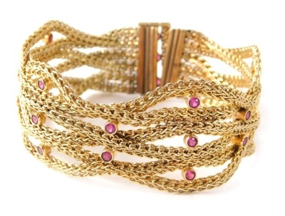 An Eastern inspired bracelet, of twist and rope twist decoration, set with rubies in rows of twos and threes, with slide clip bar, yellow metal with rubbed hallmarks, possibly 14k or 18k, 38.4g all in.