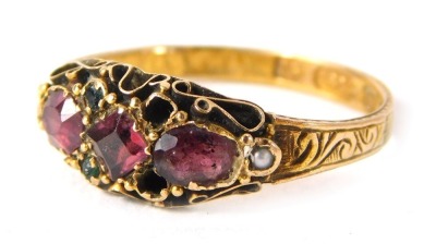 A 15ct gold ruby gypsy ring, set with two oval rubies and a square cut central ruby, with tiny emeralds and seed pearls with scroll design shoulders, ring size L½, 1.7g all in.