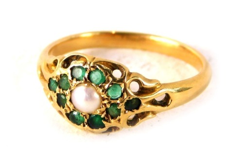 An emerald and cultured pearl dress ring, formed as a floral cluster with pierced and scroll outer border, on a yellow metal band, unmarked, believed to be 18ct gold, ring size L½, 2.5g all in.