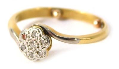 An 18ct gold and platinum twist ring, the floral cluster set with tiny diamonds, with white metal twist shoulders on a yellow metal band, with ring size markers, ring size M½, 3.3g all in.