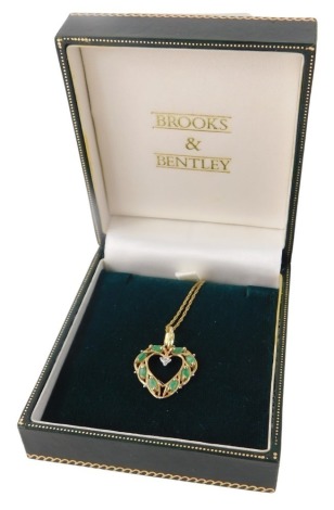 A 9ct gold emerald and diamond heart shaped pendant and chain, the pendant of crossover design, 2cm high, on a fine link neck chain, 50cm long, 2.5g all in, boxed.