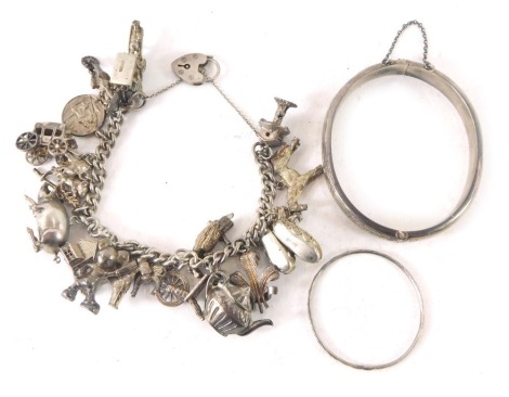 A silver hinged bangle, with floral design, a child's silver bangle and a silver charm bracelet with various charms, 108.2g all in. (3)