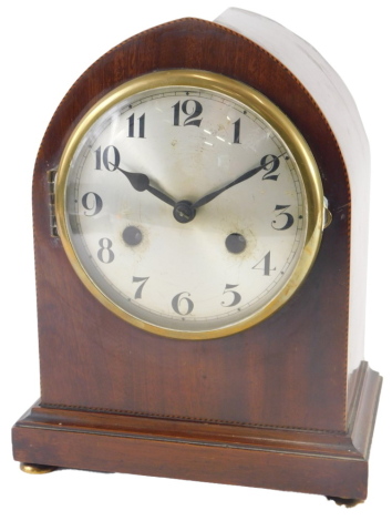 An early 20thC mahogany and chequer banded mantel clock, with an arched top and a silvered dial, 26cm high.