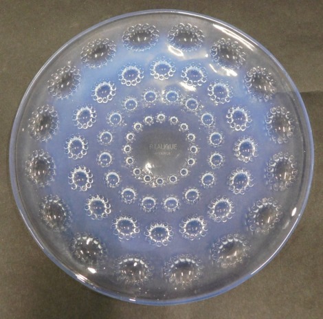 A Lalique iridescent glass plate, decorated with ovals with beaded borders, stencil mark R Lalique France, 18cm diameter.